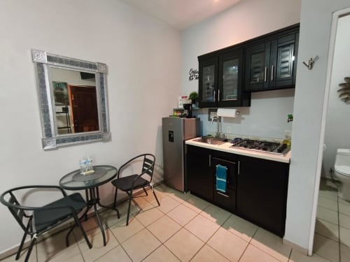 Cocina y comedor del departamento Villita Puebla en Casa Punta Perula con muebles negros, estufa y mesa con asientos
