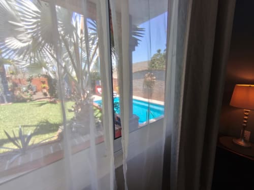 Vista a través de cortinas translúcidas de la piscina, palmeras y jardín manicurado de Casa Punta Perula Boutique Hotel
