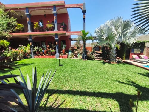 Villa boutique Casa Punta Perula con fachada de barro, jardín exuberante, palmeras y vistas a la piscina en Punta Perula, México