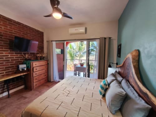 Villa espaciosa con dormitorio amplio, cama de madera, pared de ladrillo, balcón, ventilador de techo y diseño moderno en Casa Punta Perula