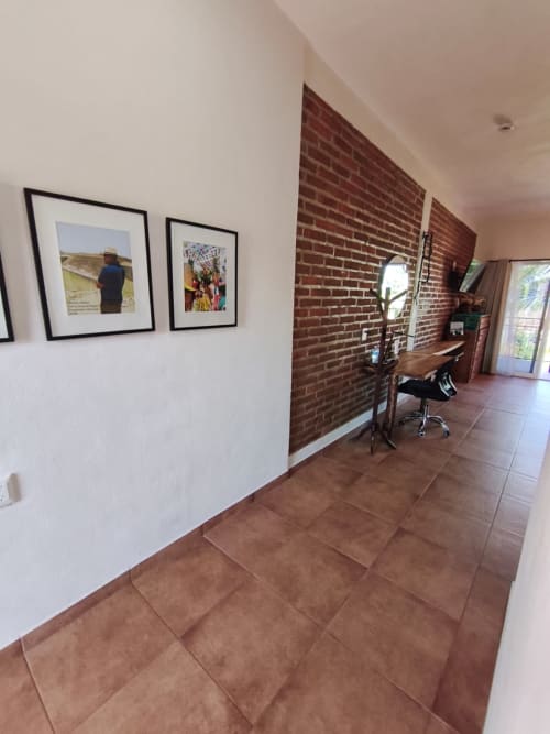 Pasillo moderno en villa de Punta Perula con azulejos de barro, paredes blancas, acento de ladrillo visto, cuadros enmarcados, área de trabajo y