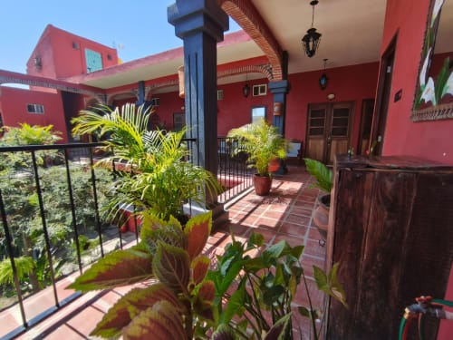 Radiante patio colonial rojo en Casa Punta Perula con plantas en macetas, azulejos de barro y puertas de madera en Punta Perula,