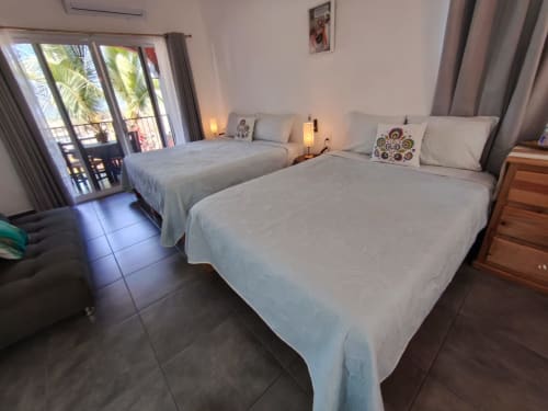 Amplio dormitorio de villa en Casa Punta Perula con dos camas, pisos de azulejo, acceso a balcón y vistas tropicales