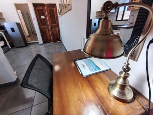 Espacio de trabajo en boutique hotel con escritorio de madera, lámpara de escritorio de latón y silla negra en Casa Punta Perula, Punta Perula, México