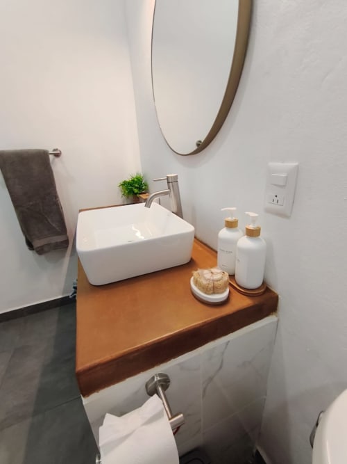 Moderno lavamanos en Casa Punta Perula con fregadero blanco, encimera de madera, artículos de tocador y espejo redondo en Punta Perula