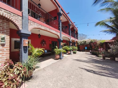 Patio colonial rojo en Casa Punta Perula Boutique Hotel, Punta Perula México, con jardines tropicales y arcos