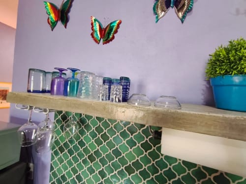 Estante rústico de madera en villa Villita Guanajuato con botellas coloridas, mariposas decorativas y planta en maceta en Casa