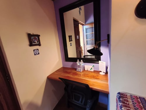 Área de trabajo en villa Villita Guanajuato con escritorio de madera, espejo, botellas de agua y vista a las montañas en Casa Punta Perula