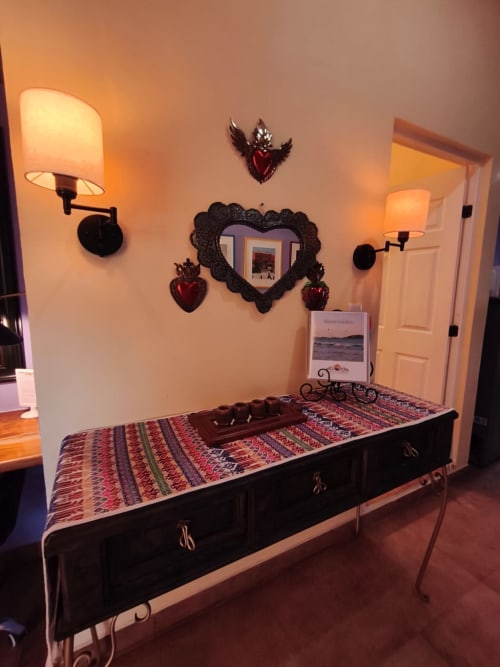 Ropa de cama a rayas coloridas en cama de marco negro con corazones rojos decorativos y espejo en paredes color crema en la villa Villita Guanajuato