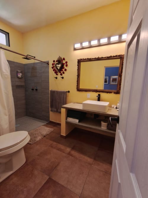 Baño amarillo brillante en villa Villita Guanajuato con lavabo tipo vessel, ducha walk-in y vistas al océano en Casa Punta Perula