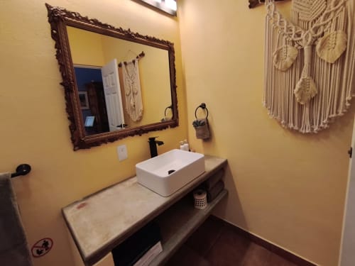 Baño moderno en villa Villita Guanajuato de Casa Punta Perula con paredes amarillas, lavabo de cerámica, espejo ornamental y macramé