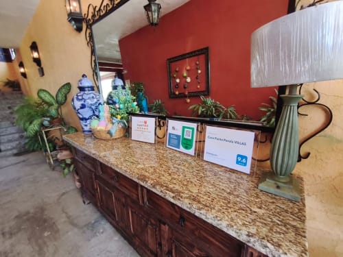 Mostrador de recepción de Casa Punta Perula con encimera de granito, jarrones azules decorativos, plantas y señalética de bienvenida mexicana