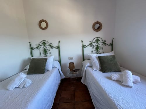 Dos camas con cabeceras verdes ornamentadas y ropa de cama blanca en la casita Casa de la Aguadora, Iznatoraf