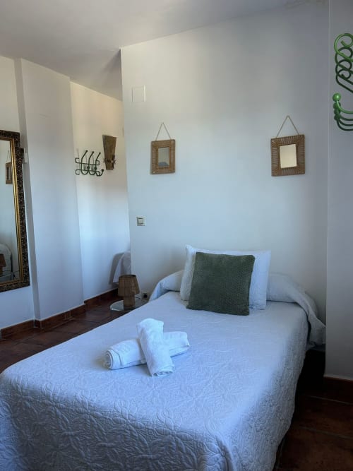 Luminoso dormitorio en casita El Granero de Casa de la Aguadora, Iznatoraf, con cama blanca acolchada, almohada verde y