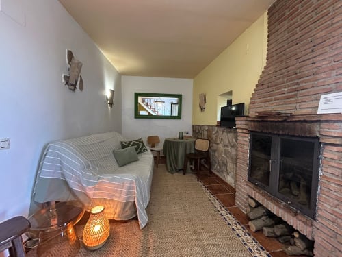 Acogedora habitación con chimenea, sofá, TV y vistas a la montaña en Casa de la Aguadora, Iznatoraf
