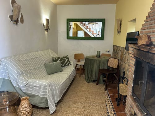 Acogedora sala de estar de la Casa de la Aguadora con sofá, chimenea y vistas a las montañas, Iznatoraf España