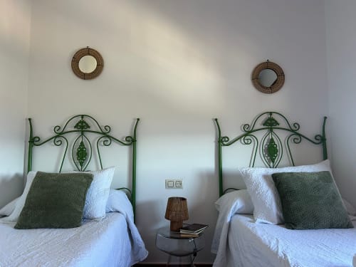Camas gemelas con cabeceros verdes ornamentados y ropa de cama blanca en una luminosa habitación de Casa de la Aguadora, Iznatoraf