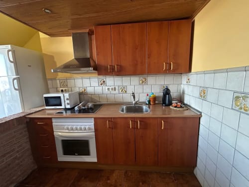 Cocina completamente equipada en la casita El Granero con gabinetes de madera, salpicadero de azulejos blancos, estufa, fregadero y diseño moderno