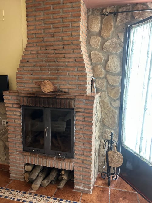 Chimenea de ladrillo con puertas de cristal negro y conducto de piedra en la casita El Granero de Casa de la Aguadora, Iznatoraf