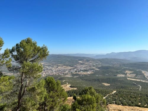 Vista panorámica del valle de montaña desde la casita Casa de la Aguadora en Iznatoraf, España, con laderas boscosas y el pueblo abajo