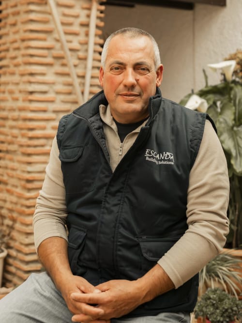 Professional man in Escanda Building Solutions vest at hotel entrance with brick wall background