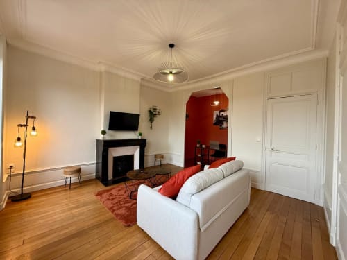 Élégant salon Haussmannien à Le 48 Roanne avec cheminée, canapé blanc et touches de rouge