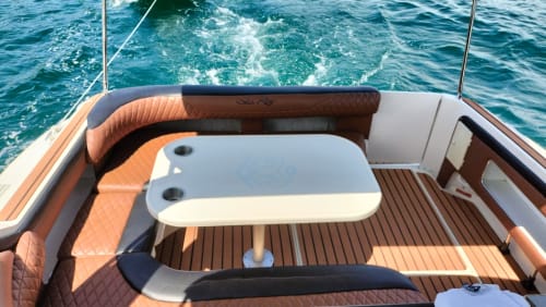 Interior de lujo de yate con asientos naranja y madera en La Isla Acapulco Diamante, aguas turquesas del océano al fondo
