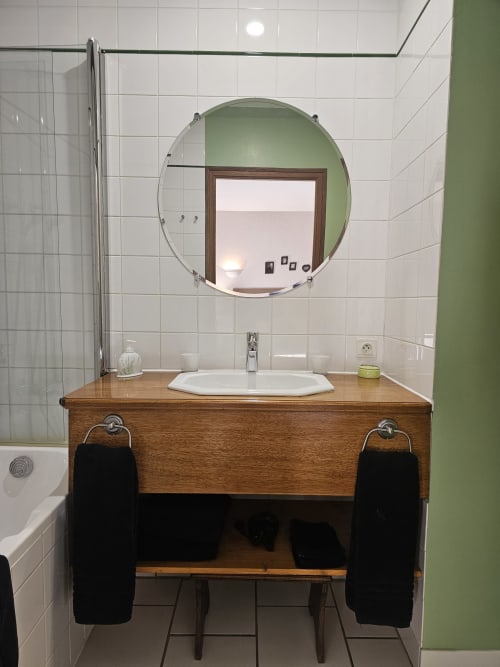 Modern bathroom vanity with wooden cabinet and round mirror at Château de Ribourdin, Chevannes