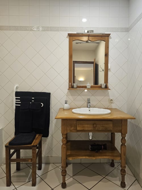 Bathroom vanity with wooden sink table, round basin, and framed mirror at Château de Ribourdin B&B in Chevannes, France