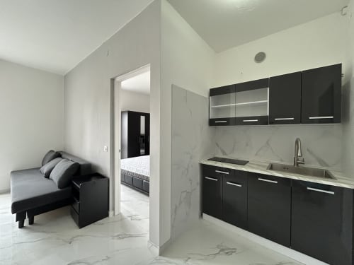Cucina moderna e zona living della suite Loft Elegans 2 all'hotel Anthea di Lignano Sabbiadoro, con arredamenti neri e dettagli in marmo