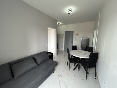 Moderno loft all'Anthea Hotel di Lignano Sabbiadoro con zona living, tavolo da pranzo, divano nero e pavimenti in marmo