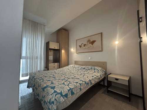 Camera dell'Hotel Anthea, Lignano Sabbiadoro: letto con motivi floreali, armadio, finestra con vista mare e servizi moderni