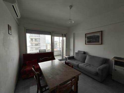 Soggiorno moderno dell'hotel Anthea a Lignano Sabbiadoro con balcone vista mare, divano grigio e zona pranzo
