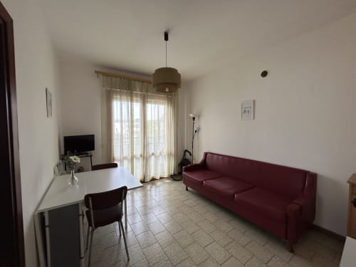 Comfort apartment living room at Anthea hotel in Lignano Sabbiadoro with burgundy sofa, dining area, and balcony access