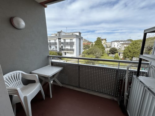 Balcony terrace at Anthea hotel in Lignano Sabbiadoro with white chair, table, and residential neighborhood view