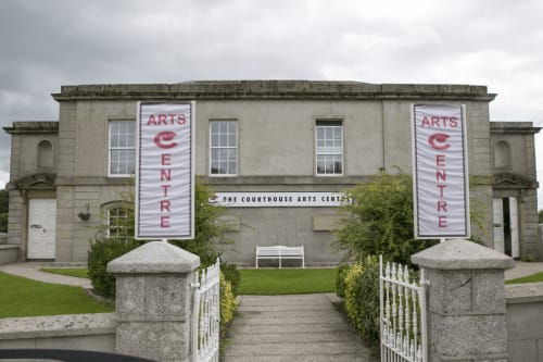 The Courthouse Arts Centre in Wicklow, Ireland - a historic stone building with red banner signage and white gates