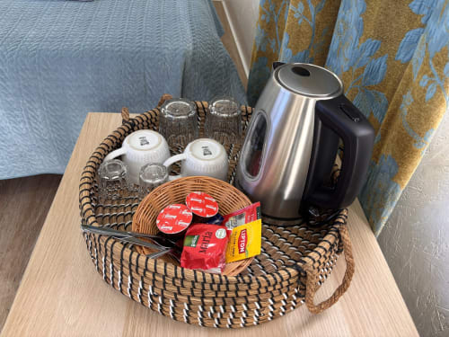 Chaleira elétrica com xícaras, cápsulas de café e chás em cesta trançada na cabana glamping Arrabia Guest Houses