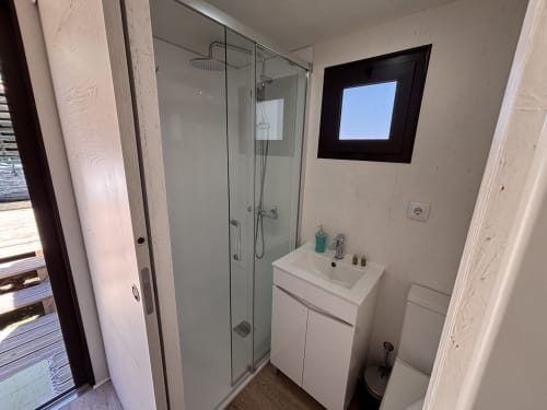 Banheiro moderno na Glamping Arrabia Guest Houses com chuveiro, pia e claraboia com vista para o rio em Castelo de