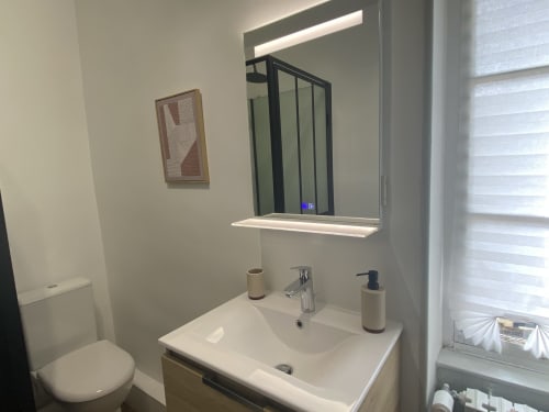 Modern bathroom at Clos Ceres B&B with illuminated mirror, white sink, and toilet in Viré, Bourgogne