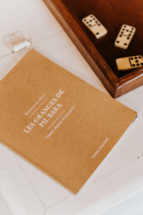 Livre français et dominos sur une table aux Granges de Pil Bara B&B à Langoat