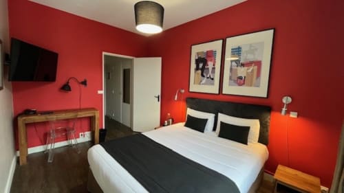 Chambre confortable à l'Hôtel Des Cèdres à Orléans : murs rouges, lit queen-size, TV et vue sur la ville