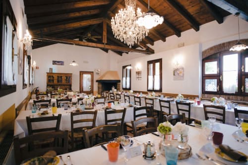 Elegante sala da pranzo di Villa Mocenigo con lampadario, travi a vista, tovaglie bianche e camino a Mirano