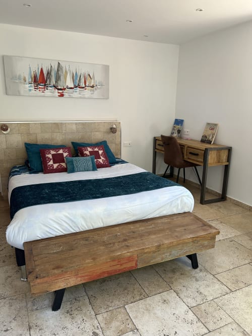 Dormitorio moderno en Casa Di Floumy en Calvi con arte temático náutico, ropa de cama en azul verdoso y burdeos, banco de madera y azulejos