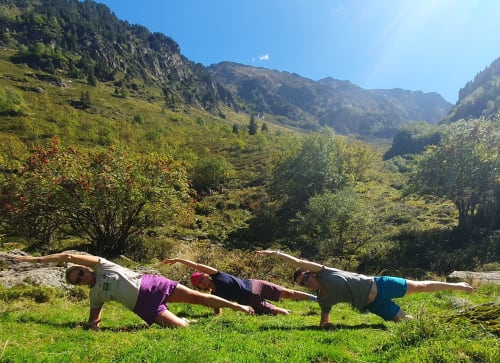 Trois personnes en planche sur l'herbe avec la vallée montagnarde d'Ax-les-Thermes en arrière-plan aux Hauts d'En Castel