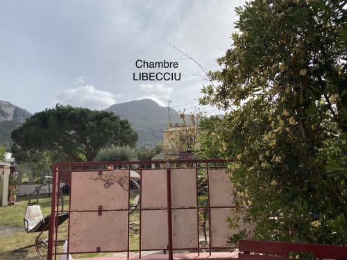 Casa Di Floumy BnB en Calvi con vistas montañosas, puerta roja y exuberante vegetación mediterránea