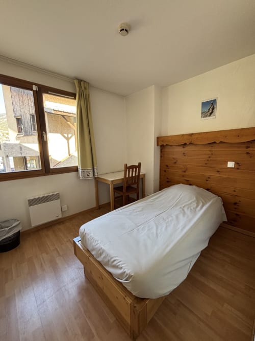Chambre simple au Centre Sportif d'Altitude de Briançon avec lit simple, bureau et vue sur les montagnes
