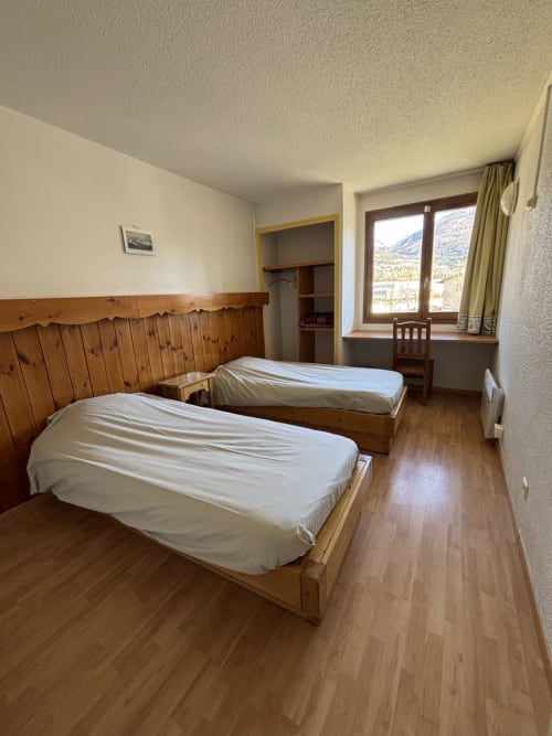 Chambre double lumineuse au Centre Sportif d'Altitude Briançon avec lits en bois, vue montagne et parquet
