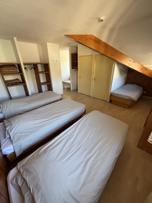 Chambre spacieuse quintuple au centre de sports de Briançon avec lits multiples et poutres en bois