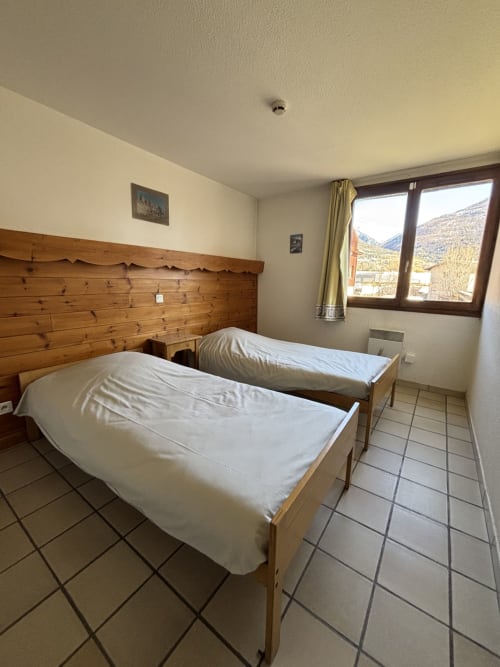 Chambre twin avec tête de lit en bois au Centre Sportif d'Altitude de Briançon, vue sur les montagnes par la fenêtre