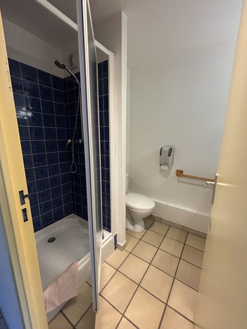 Salle de bain avec douche, toilettes et carrelage beige à l'hôtel Centre Sportif d'Altitude de Briançon